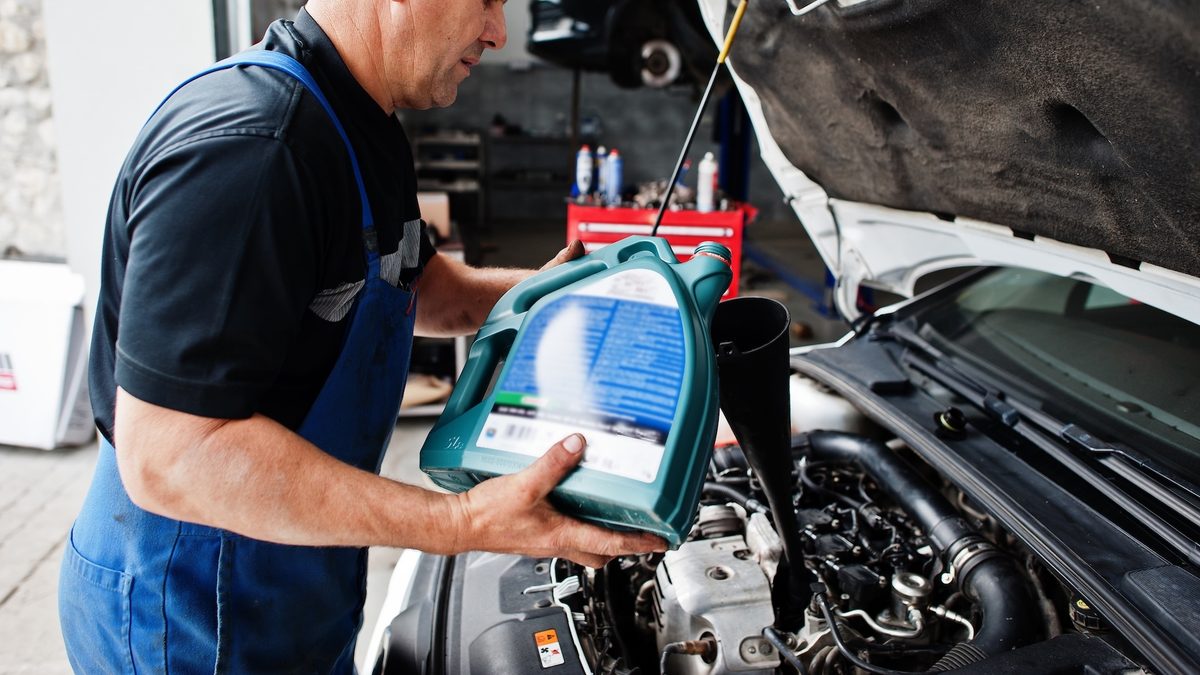 car-repair-maintenance-theme-mechanic-uniform-working-auto-service-pouring-new-motor-oil.j